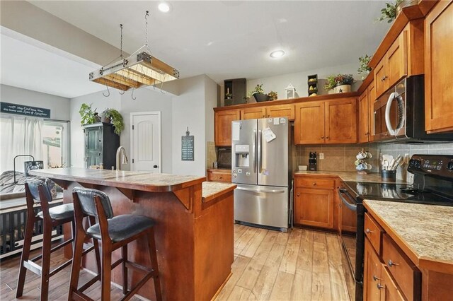 207 N Laurel St Unit 5D, Gardner, KS 66030 - kitchen with black / electric stove, stainless steel fridge, light countertops, brown cabinetry, and backsplash