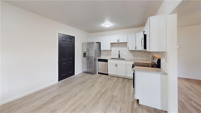 118 W Hickory St, Nevada, MO 64772 - kitchen with stainless steel appliances, backsplash, light wood finished floors, and white cabinets
