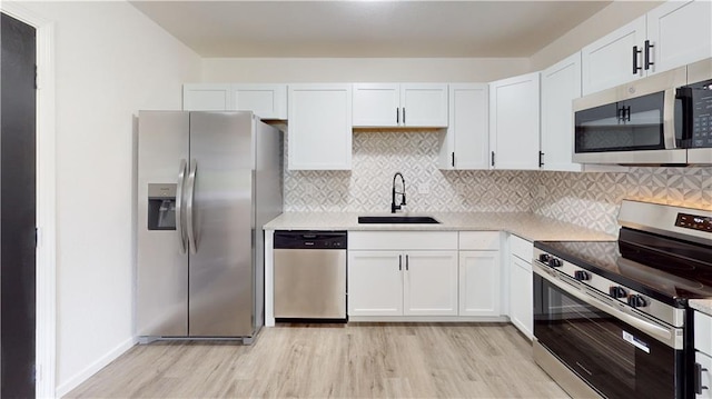 118 W Hickory St, Nevada, MO 64772 - kitchen featuring appliances with stainless steel finishes, light wood-type flooring, white cabinets, light countertops, and decorative backsplash