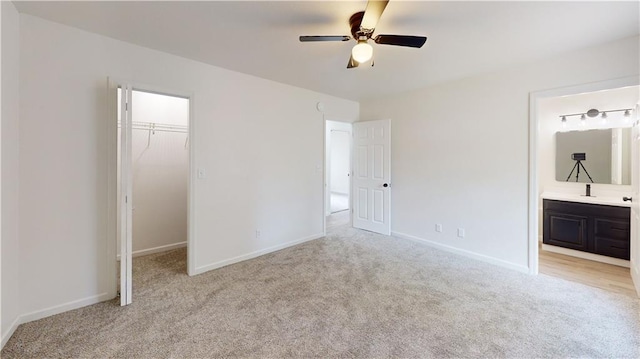 118 W Hickory St, Nevada, MO 64772 - unfurnished bedroom featuring light carpet, a spacious closet, a closet, ensuite bathroom, and a ceiling fan