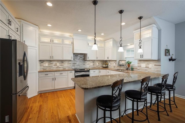 35705 E Rd Mize Rd, Oak Grove, MO 64075 - kitchen with appliances with stainless steel finishes, a peninsula, white cabinetry, light wood-style floors, and glass insert cabinets