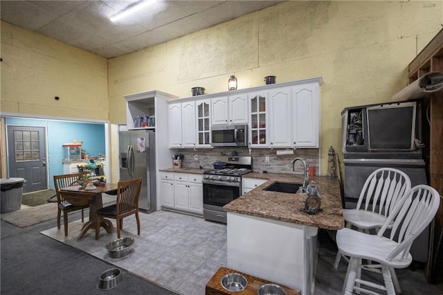 35705 E Rd Mize Rd, Oak Grove, MO 64075 - kitchen with appliances with stainless steel finishes, a towering ceiling, white cabinetry, decorative backsplash, and glass insert cabinets