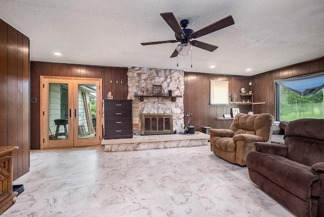 4207 10th Ave, Leavenworth, KS 66048 - living room with a textured ceiling, wood walls, ceiling fan, a stone fireplace, and recessed lighting