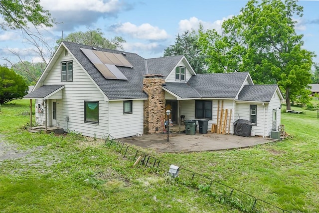4207 10th Ave, Leavenworth, KS 66048 - rear view of house with a shingled roof, roof mounted solar panels, a patio, and a chimney