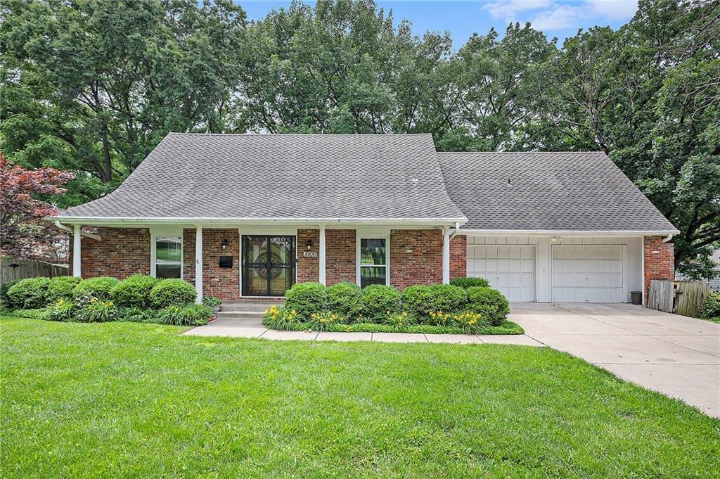 10100 El Monte St, Overland Park, KS 66207 - view of front facade featuring an attached garage, driveway, brick siding, and roof with shingles