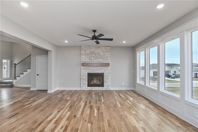 6018 Arapahoe St, Shawnee, KS 66226 - unfurnished living room with light wood-style flooring, ceiling fan, stairs, a stone fireplace, and recessed lighting