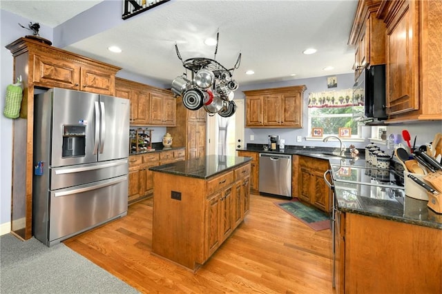 4316 Grand Ave, Leavenworth, KS 66048 - kitchen with stainless steel appliances, brown cabinets, a kitchen island, a sink, and dark stone countertops