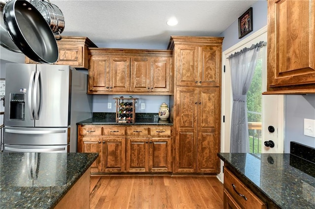 4316 Grand Ave, Leavenworth, KS 66048 - kitchen featuring stainless steel fridge with ice dispenser, light wood finished floors, brown cabinetry, dark stone countertops, and recessed lighting