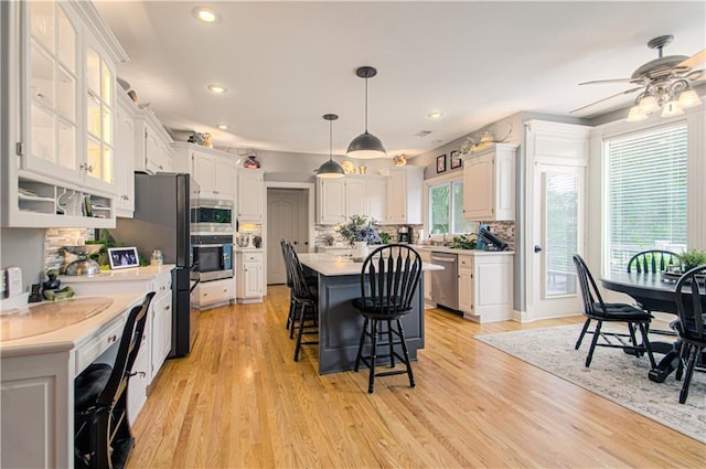 18765 S Alden St, Olathe, KS 66062 - kitchen with stainless steel appliances, a kitchen bar, white cabinetry, a center island, and light countertops