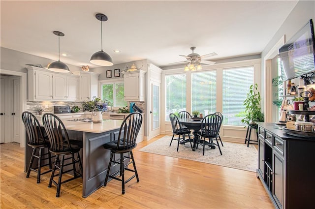 18765 S Alden St, Olathe, KS 66062 - kitchen featuring a breakfast bar, white cabinetry, light wood-style floors, a kitchen island, and decorative light fixtures