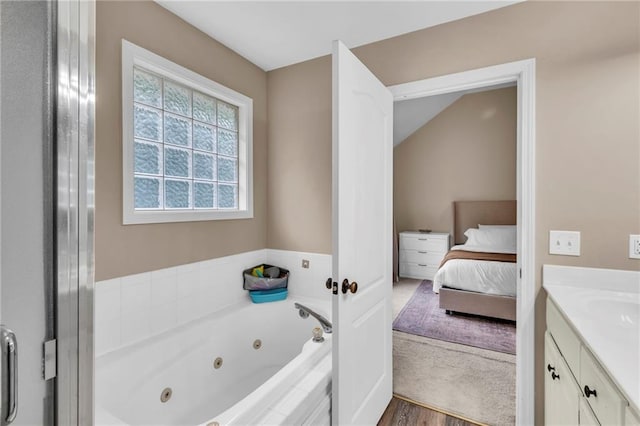 1610 Renea Ct, Kearney, MO 64060 - ensuite bathroom featuring vanity, a jetted tub, lofted ceiling, and wood finished floors