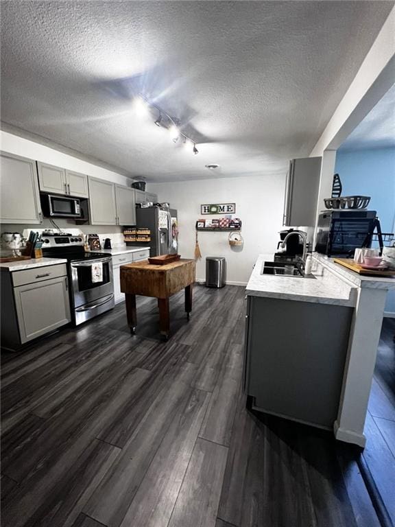 414 S 3rd St, Humboldt, KS 66748 - kitchen with appliances with stainless steel finishes, gray cabinetry, a textured ceiling, and dark wood-type flooring