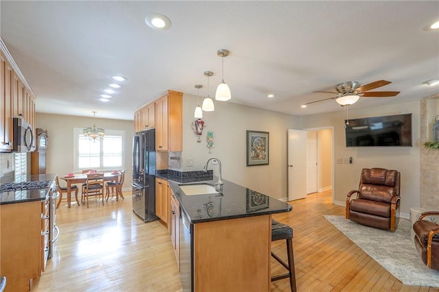 115 NE Green St, Lees Summit, MO 64063 - kitchen with freestanding refrigerator, open floor plan, range with gas stovetop, light wood-type flooring, and a kitchen bar