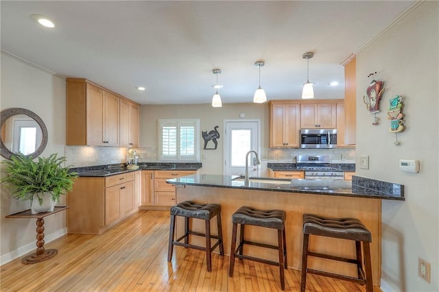 115 NE Green St, Lees Summit, MO 64063 - kitchen with appliances with stainless steel finishes, a peninsula, backsplash, light wood finished floors, and recessed lighting