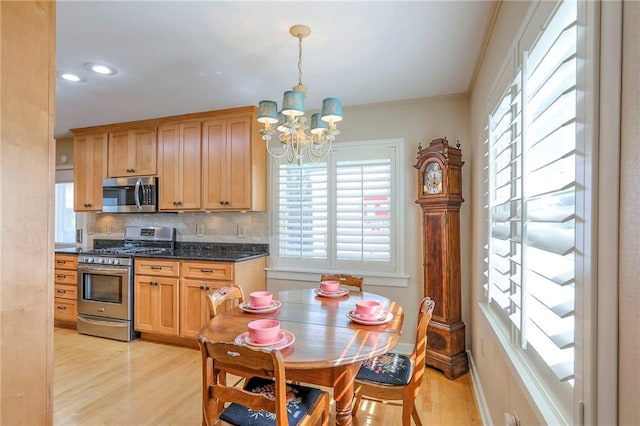 115 NE Green St, Lees Summit, MO 64063 - kitchen with stainless steel appliances, light wood-type flooring, a chandelier, decorative backsplash, and decorative light fixtures