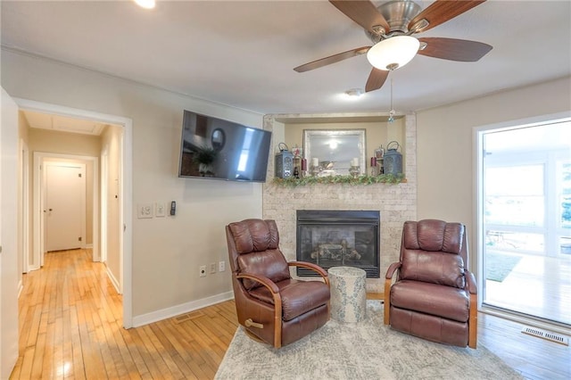 115 NE Green St, Lees Summit, MO 64063 - sitting room featuring light wood finished floors, a brick fireplace, and a ceiling fan