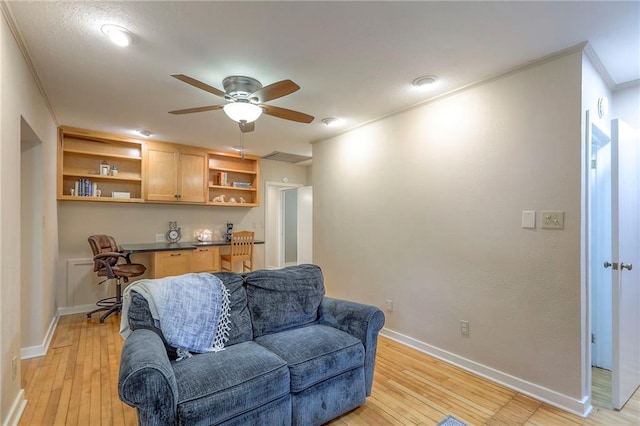 115 NE Green St, Lees Summit, MO 64063 - living area featuring built in desk, ornamental molding, ceiling fan, and light wood-style floors