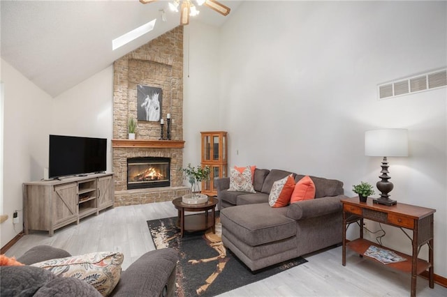 307 E Gore Rd, Raymore, MO 64083 - living room featuring ceiling fan, wood finished floors, a stone fireplace, a skylight, and high vaulted ceiling