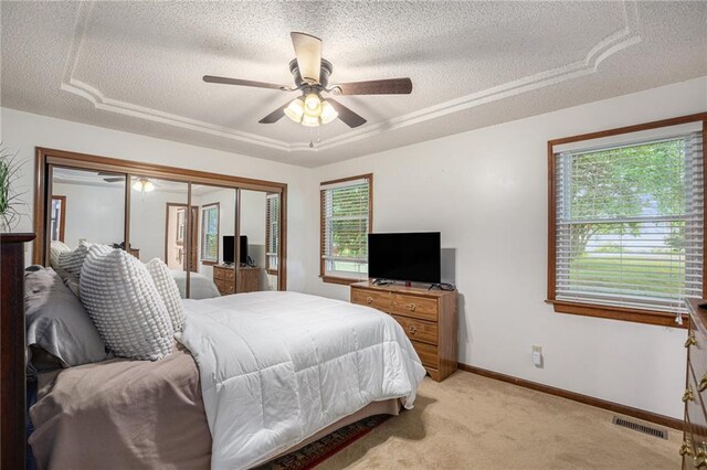 307 E Gore Rd, Raymore, MO 64083 - bedroom with a textured ceiling, light carpet, a closet, a ceiling fan, and a tray ceiling
