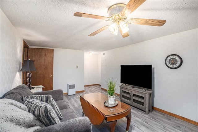 307 E Gore Rd, Raymore, MO 64083 - living room featuring light wood-style floors, a textured ceiling, a ceiling fan, and baseboards
