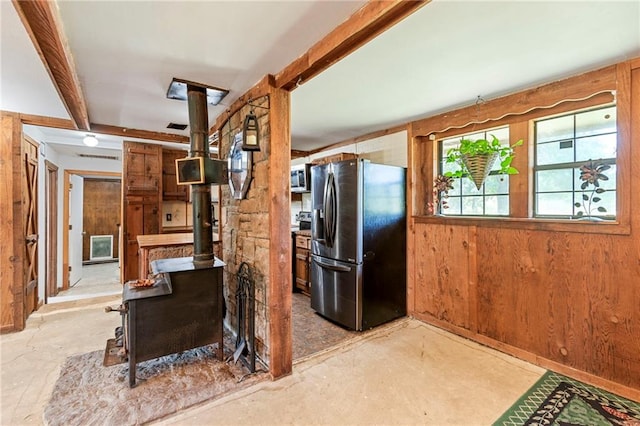 5470 SE Downing Rd, Lathrop, MO 64465 - kitchen with appliances with stainless steel finishes, wood walls, a wood stove, concrete flooring, and beam ceiling