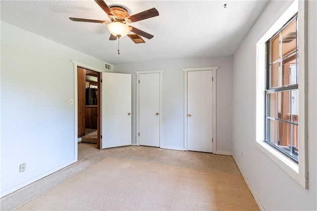 5470 SE Downing Rd, Lathrop, MO 64465 - unfurnished bedroom featuring two closets, a textured ceiling, and a ceiling fan