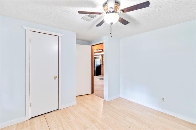 5470 SE Downing Rd, Lathrop, MO 64465 - unfurnished bedroom featuring wood finished floors, a textured ceiling, freestanding refrigerator, and a ceiling fan