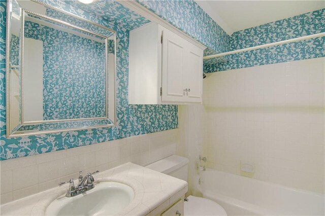 9920 Juniper Ln, Overland Park, KS 66207 - full bathroom featuring wallpapered walls, toilet, vanity,  shower combination, and tile walls