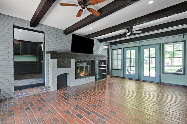 3200 NW 51st Ter, Blue Springs, MO 64015 - unfurnished living room featuring a ceiling fan, plenty of natural light, beam ceiling, a fireplace, and brick floors