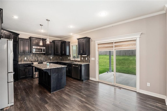 1532 SW Cross Creek Dr, Lees Summit, MO 64082 - kitchen with appliances with stainless steel finishes, tasteful backsplash, a kitchen island, dark wood-type flooring, and crown molding