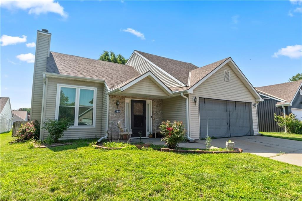 380 N Sumac St, Gardner, KS 66030 - view of front of home with a garage, a chimney, driveway, a front yard, and roof with shingles