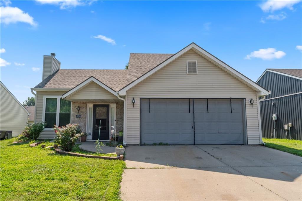 380 N Sumac St, Gardner, KS 66030 - view of front of home featuring a chimney, a front lawn, a garage, a shingled roof, and driveway