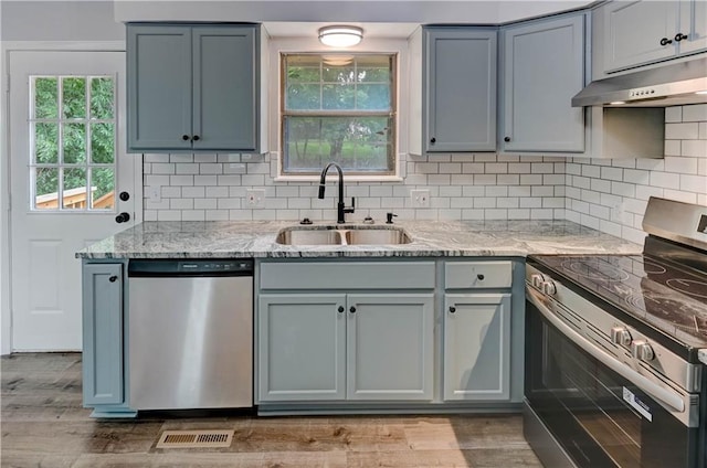 113 SE 250th Rd, Warrensburg, MO 64093 - kitchen featuring appliances with stainless steel finishes, under cabinet range hood, light stone countertops, tasteful backsplash, and light wood-style floors
