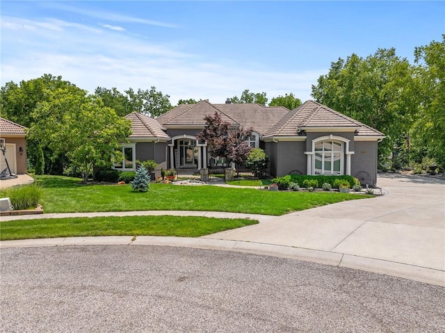 8709 Pine St, Lenexa, KS 66220 - view of front of home featuring a front lawn, a tiled roof, stucco siding, and driveway