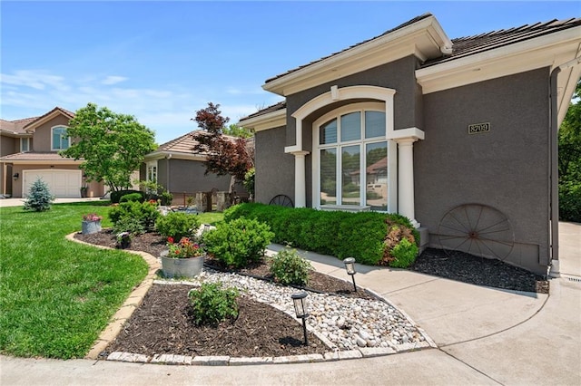 8709 Pine St, Lenexa, KS 66220 - view of side of property featuring a tile roof, stucco siding, a lawn, and a garage