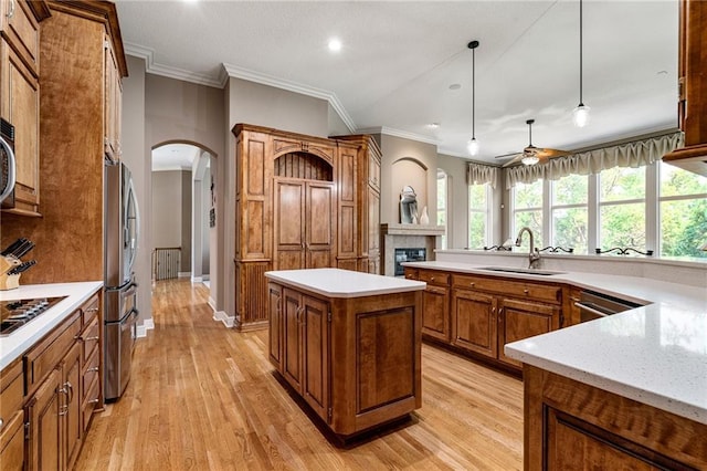 8709 Pine St, Lenexa, KS 66220 - kitchen with stainless steel appliances, ornamental molding, brown cabinetry, a kitchen island, and light wood-style flooring
