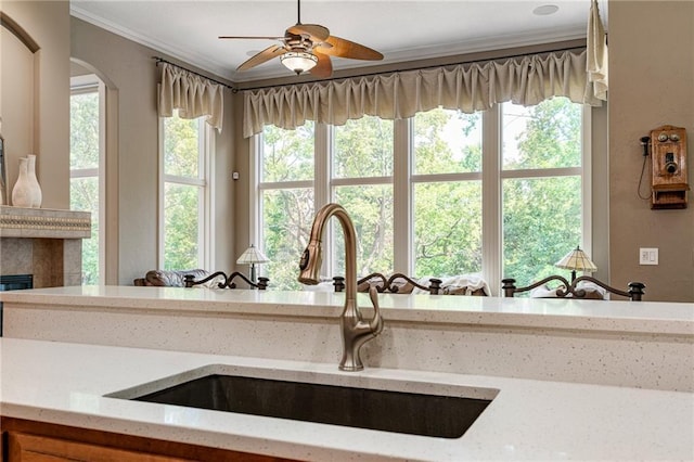 8709 Pine St, Lenexa, KS 66220 - kitchen with crown molding, a ceiling fan, light stone counters, and a glass covered fireplace