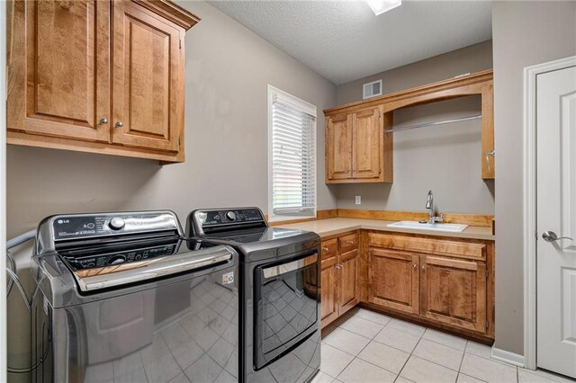 8709 Pine St, Lenexa, KS 66220 - laundry room featuring washing machine and clothes dryer, cabinet space, light tile patterned floors, and a textured ceiling