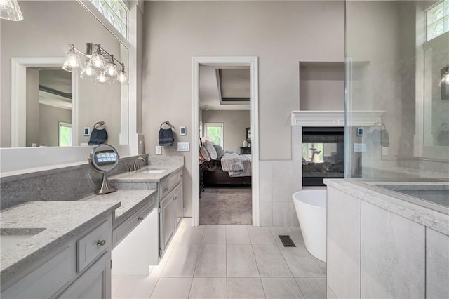 8709 Pine St, Lenexa, KS 66220 - bathroom with double vanity, connected bathroom, a freestanding bath, tile patterned floors, and plenty of natural light
