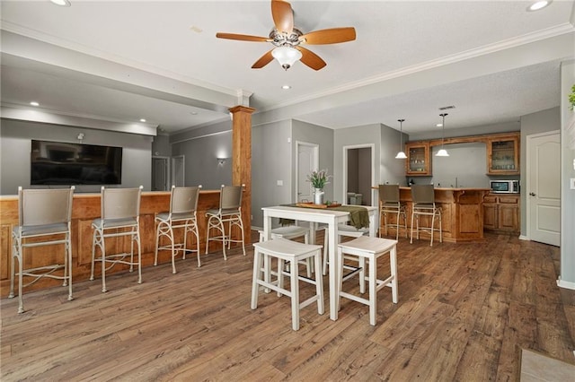 8709 Pine St, Lenexa, KS 66220 - dining space with bar with sink, wood finished floors, ornamental molding, a ceiling fan, and recessed lighting