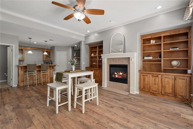 8709 Pine St, Lenexa, KS 66220 - dining space featuring a tile fireplace, light wood finished floors, a ceiling fan, ornamental molding, and recessed lighting
