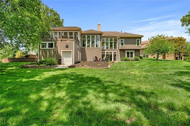 8709 Pine St, Lenexa, KS 66220 - back of property featuring a sunroom, a chimney, a garage, a yard, and stucco siding