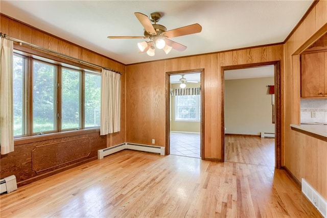 3437 Shrine Park Rd, Leavenworth, KS 66048 - unfurnished room featuring ceiling fan, light wood finished floors, wood walls, a baseboard radiator, and crown molding