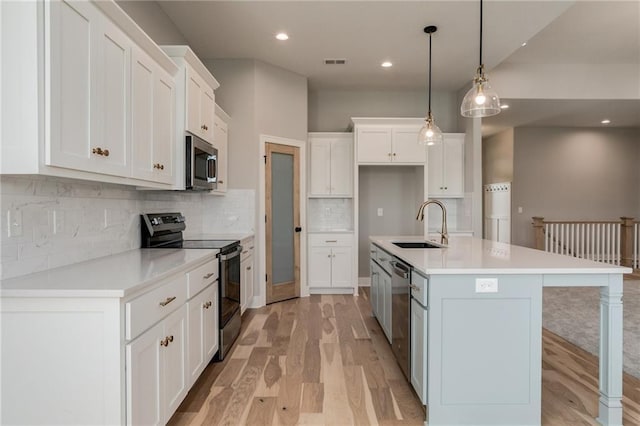 18722 W 169th Ter, Olathe, KS 66062 - kitchen with appliances with stainless steel finishes, light wood finished floors, a sink, white cabinets, and a center island with sink