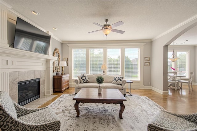 16321 Nieman Rd, Overland Park, KS 66062 - living area with ornamental molding, a ceiling fan, light wood-style floors, a textured ceiling, and a tiled fireplace