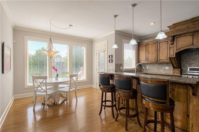 16321 Nieman Rd, Overland Park, KS 66062 - kitchen featuring healthy amount of natural light, brown cabinets, light wood-style flooring, tasteful backsplash, and crown molding