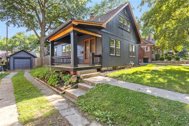 17 E 65th Ter, Kansas City, MO 64113 - view of front of property with a porch, a chimney, a detached garage, driveway, and an outbuilding