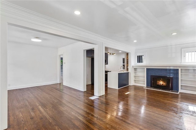 17 E 65th Ter, Kansas City, MO 64113 - unfurnished living room featuring crown molding, wood finished floors, a lit fireplace, recessed lighting, and built in shelves