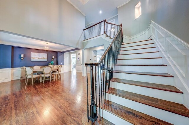 14911 Outlook Ln, Overland Park, KS 66223 - stairway with a decorative wall, crown molding, a towering ceiling, a chandelier, and wood finished floors
