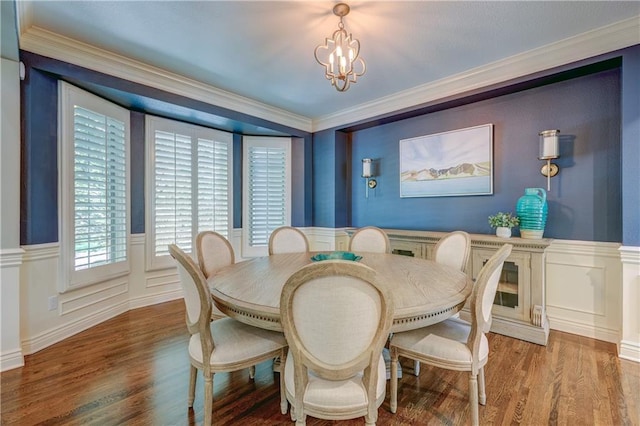14911 Outlook Ln, Overland Park, KS 66223 - dining space featuring wood finished floors, a chandelier, a decorative wall, crown molding, and wainscoting